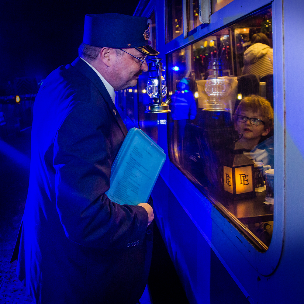 Picture of the conductor holding clipboard looking through the widow of the polar express train ride 