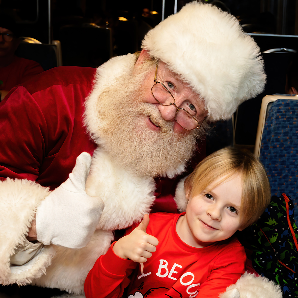 Picture of santa and young child with thumbs up on board the polar express train ride